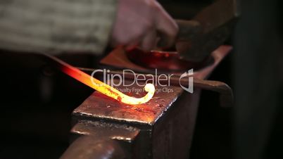 smith working with hot metal on anvil