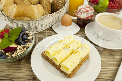Frühstück mit toast, käse, ei und früchten auf einem Tisch