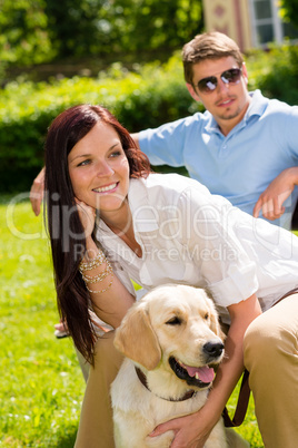 Couple sitting with golden retriever in park