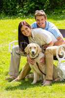 Couple sitting with golden retriever in park