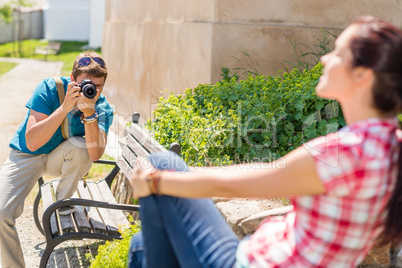 Man taking pictures of woman on bench