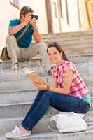 Woman sitting on stairs reading man photographing