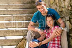 Happy young couple sitting on stairs smiling