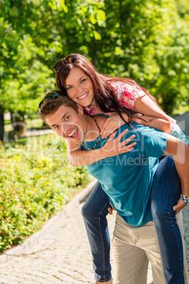 Happy couple piggyback hugging in sunny park