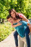 Happy couple piggyback hugging in sunny park