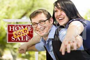 Happy Couple in Front of Sold Real Estate Sign