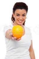 Smiling beautiful woman offering you an orange