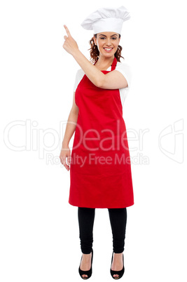 Full length portrait of female chef pointing away