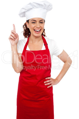 Beautiful smiling female chef indicating upwards
