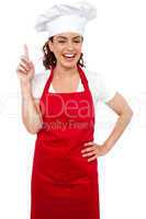 Beautiful smiling female chef indicating upwards