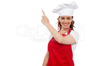 Attractive female chef pointing at copy space