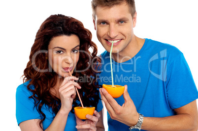 Closeup of couple cuddling and sipping orange juice