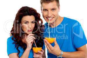 Closeup of couple cuddling and sipping orange juice