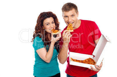 Adorable young couple relishing yummy pizza