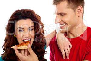 Girl enjoying pizza piece shared by her boyfriend