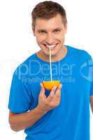 Cool guy sipping juice from half orange