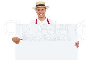 Portrait of cheerful chef pointing at placard