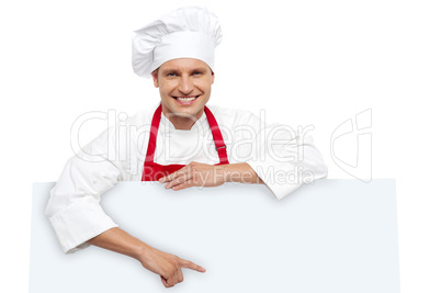 Handsome chef pointing at white billboard