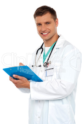 Smiling young doctor writing on clipboard