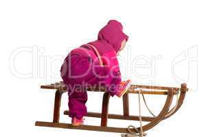 Toddler clambering onto a sled