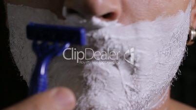 man shaves disposable razor close up