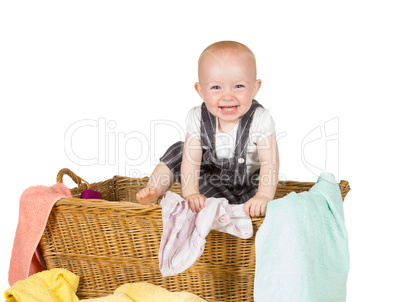 Laughing baby playing in a laundry basket