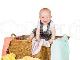 Laughing baby playing in a laundry basket