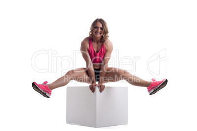 Happy woman with perfect body sit on cube
