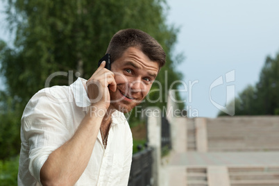 Man call by phone in summer park look at camera