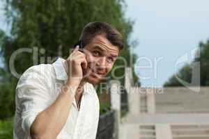 Man call by phone in summer park look at camera