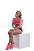 Athletic beauty woman with muscle body sit on cube