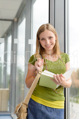 Student girl reading book standing by window