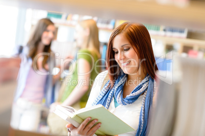 Teenage woman read among book shelves library