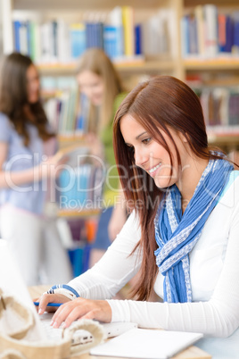 Young student girl at library typing laptop