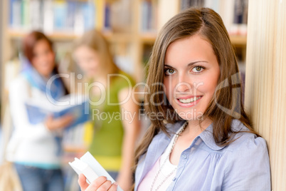 Teenage student with book at school library