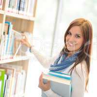 Happy student choosing books from library shelf