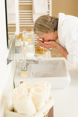 Senior woman wash face at basin bathroom