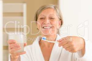 Senior woman hold toothbrush and glass water