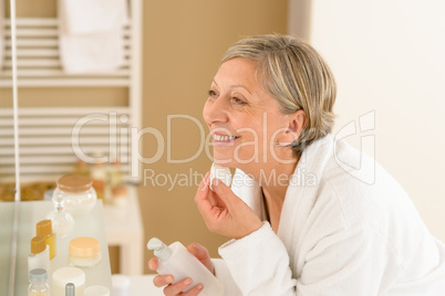 Senior woman apply face cream cotton pad
