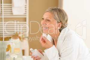 Senior woman apply face cream cotton pad