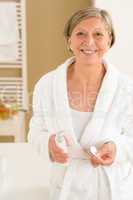 Senior woman in bathrobe hold cotton pad