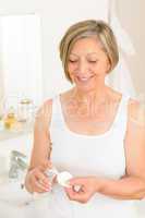 Senior woman bathroom hold cotton pad cream