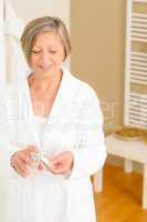Senior woman bathroom apply cream cotton pad