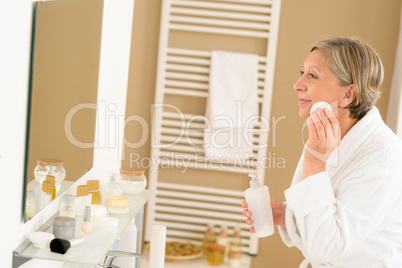 Senior woman bathroom clean face looking mirror