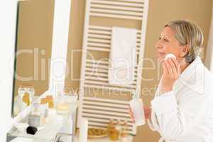Senior woman bathroom clean face looking mirror