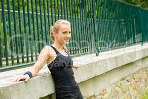 Sportive girl resting against fence after workout