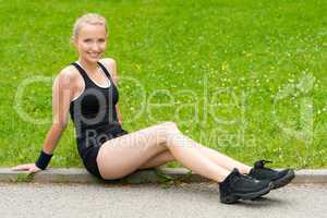 Happy young woman resting after workout sitting