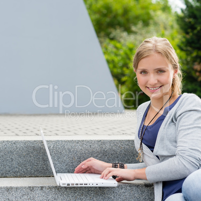 Student girl sitting on steps with laptop