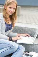 Teenage girl study with laptop sitting stairs