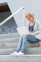 Student girl on stairs with laptop smiling